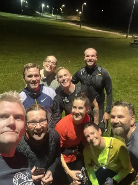 En glad grupp tar en gemensam selfie på en gräsmatta en kväll.
