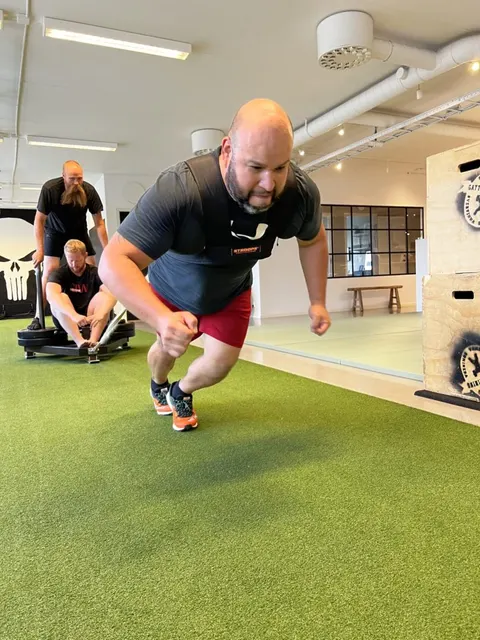 En man springer framåt i ett explosivt steg på gymmets konstgräs.