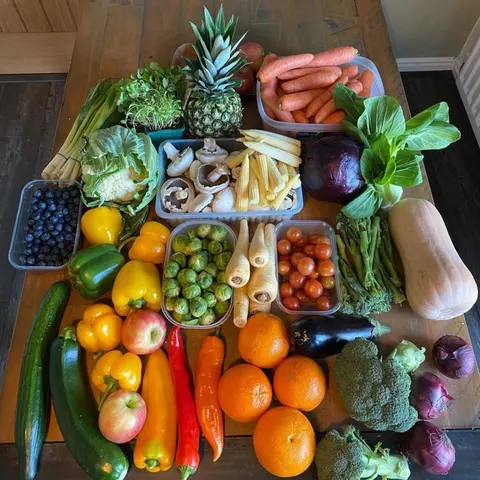 Ett bord fyllt med färska grönsaker och frukt i matlådor.