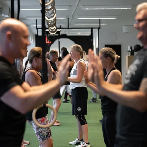 Medlemmar i ett gruppass ger varandra high five på gymmets konstgräs.