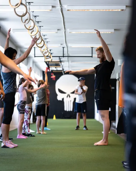 Medlemmar sträcker armarna upp mot taket under uppvärmningen i gymmet.