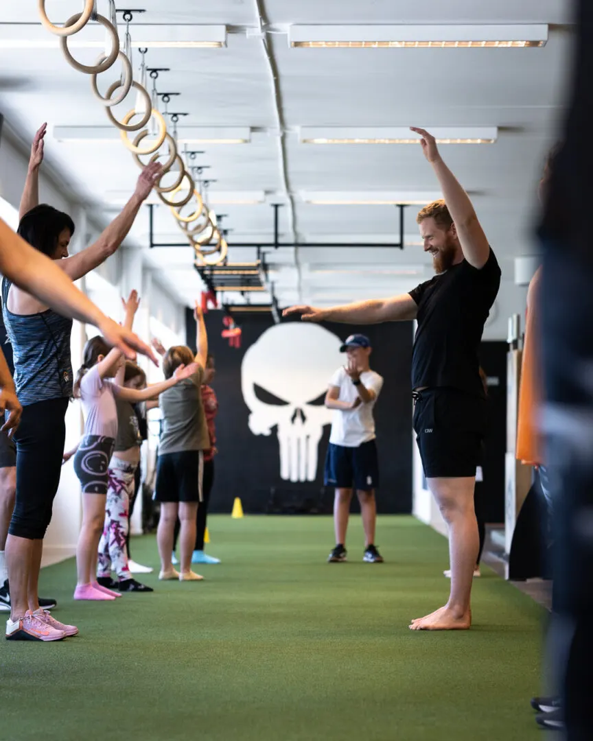 Medlemmar sträcker armarna upp mot taket under uppvärmningen i gymmet.