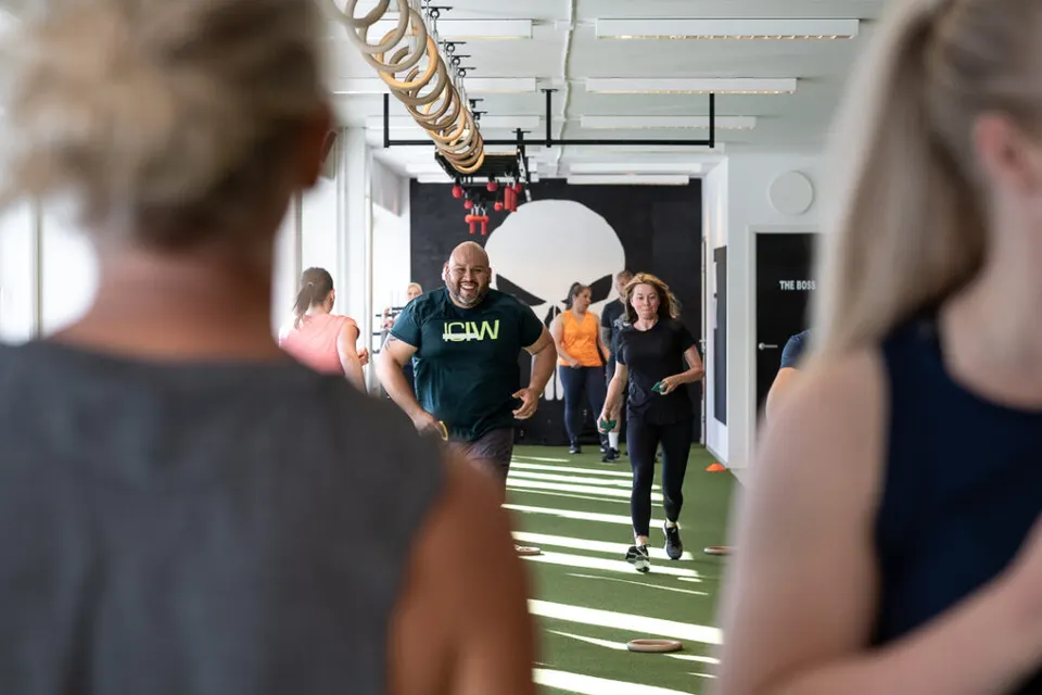 Medlemmar springer över gymmets konstgräs under ett pass, sett mellan två andra deltagare.