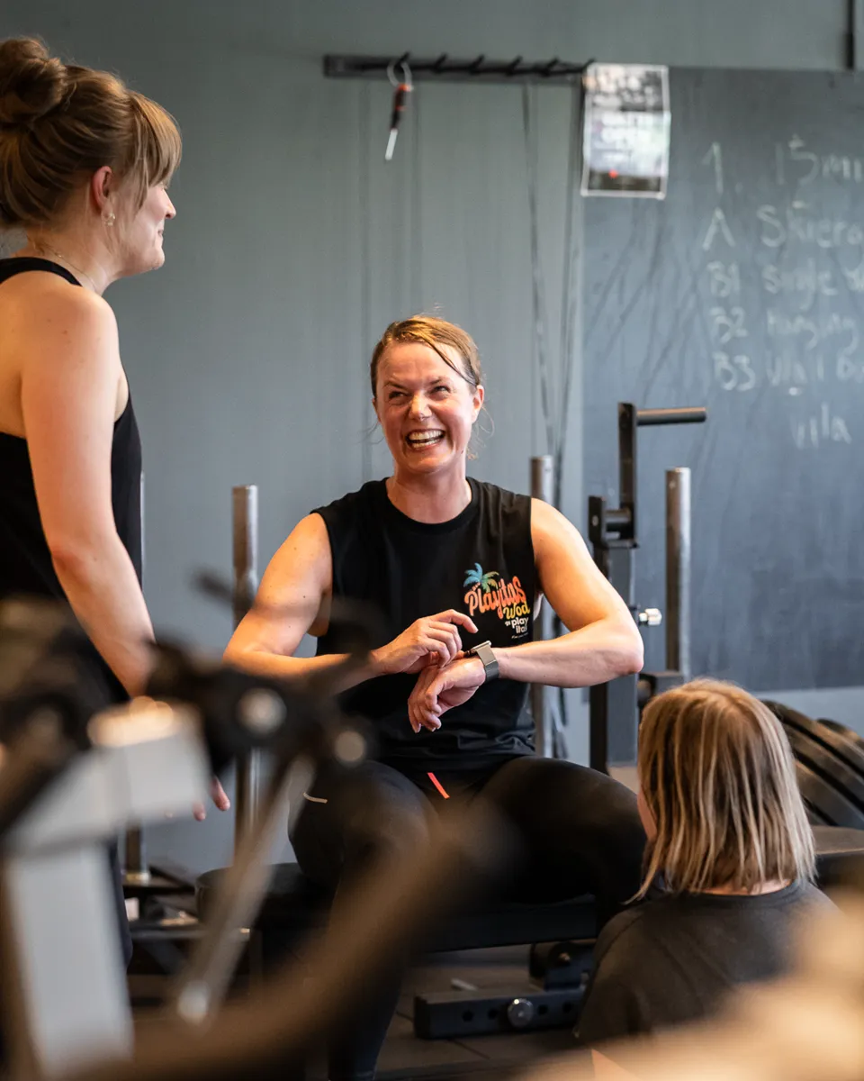En coach pratar med medlemmar i en liten grupp på gymmet.