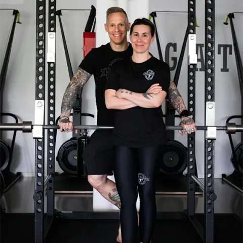 Anders och Jamina Gatti står tillsammans framför ett powerrack i sitt gym.