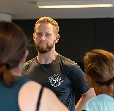 En coach samtalar med två medlemmar inne på gymmet i Årsta.