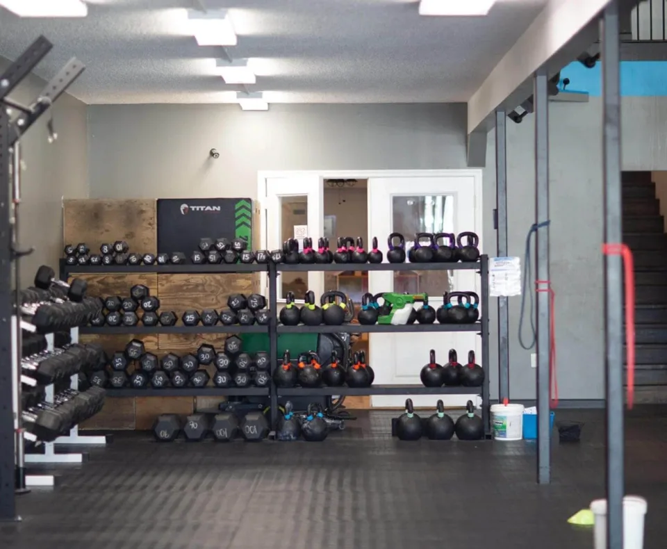 Kettlebells och hantlar i ställ längs väggen i träningssalen.